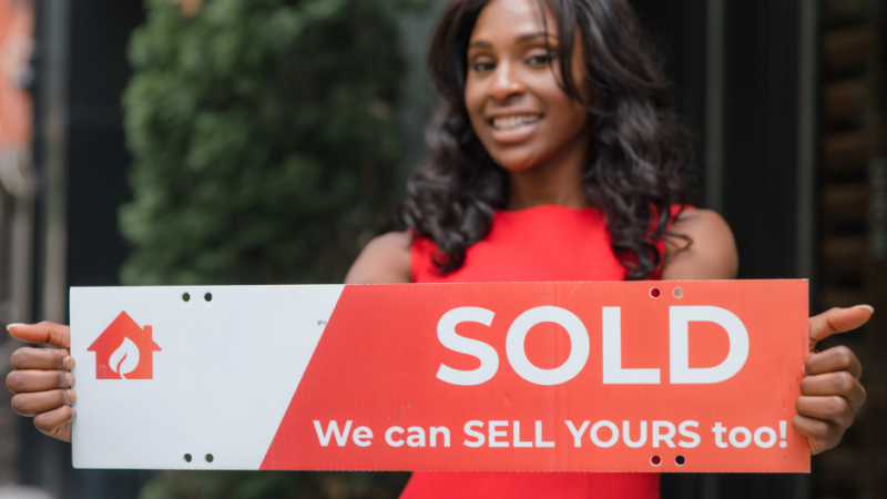 Real Estate Agent holding a sold sign